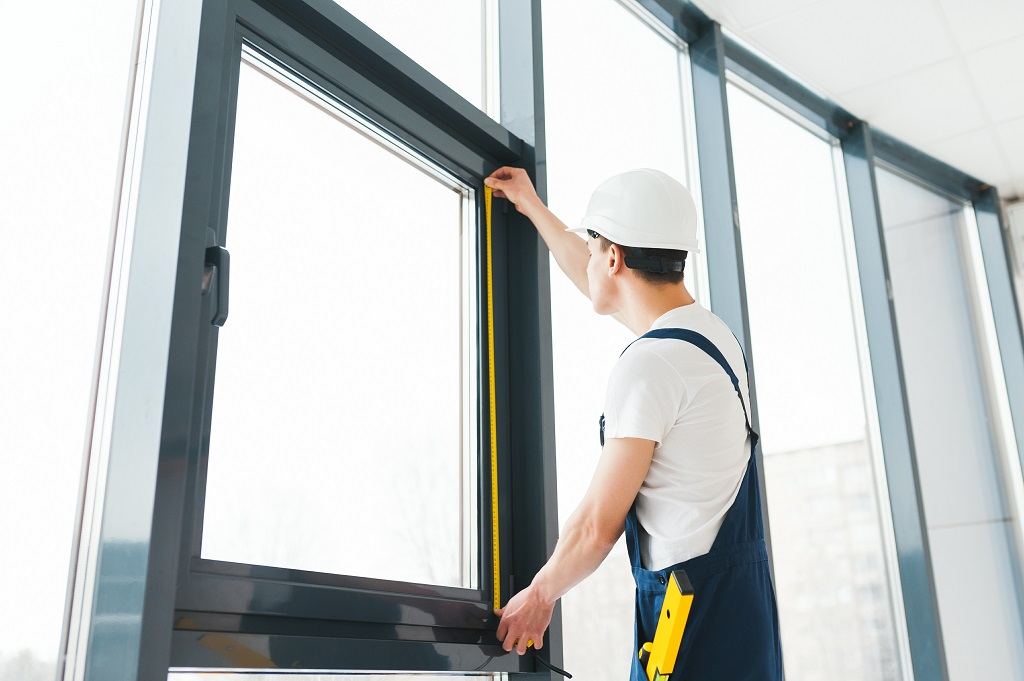 Installer measuring a new window before fitting